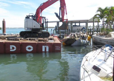 Crews pulling two sailboats off of a seawall near Stump Pass State Park